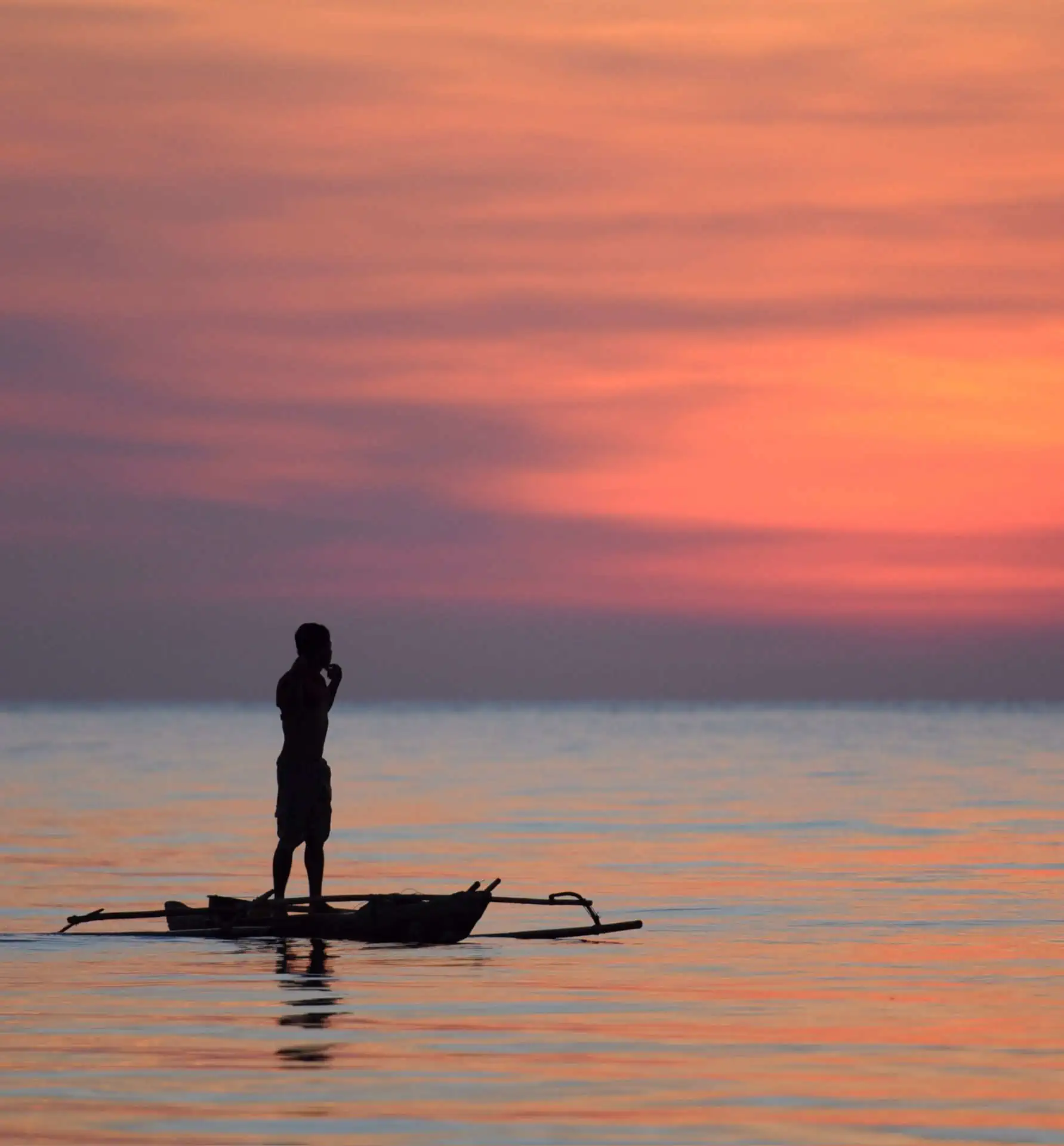 man standing on small boat with beautiful sea scenery in Indonesia